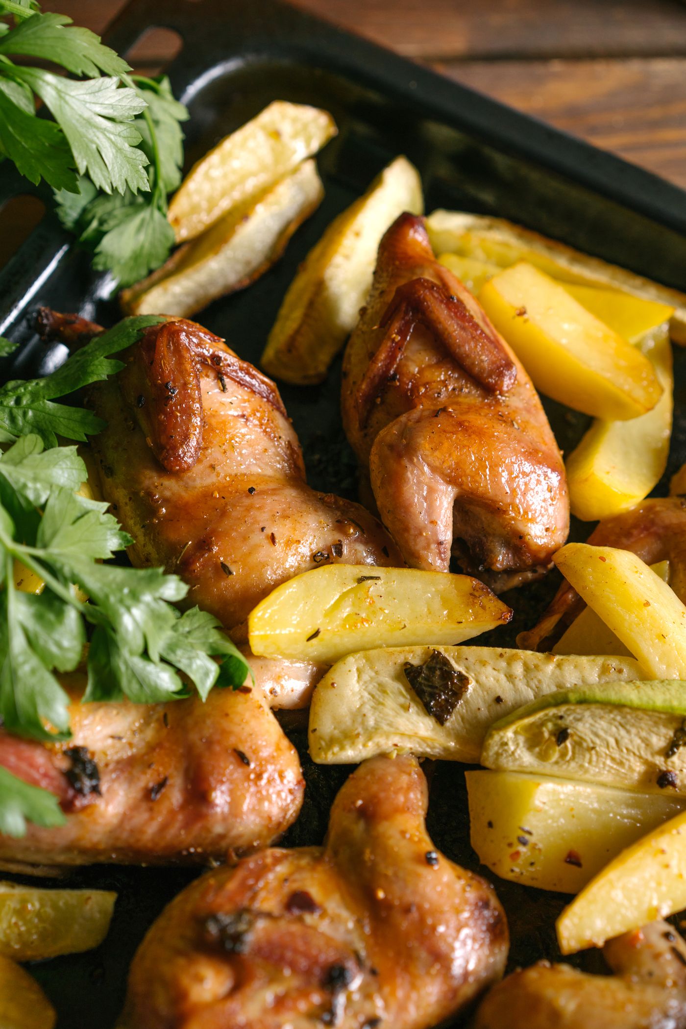 Roast chicken with potato wedges. golden skin-on chicken pieces; potato wedges; parsley.